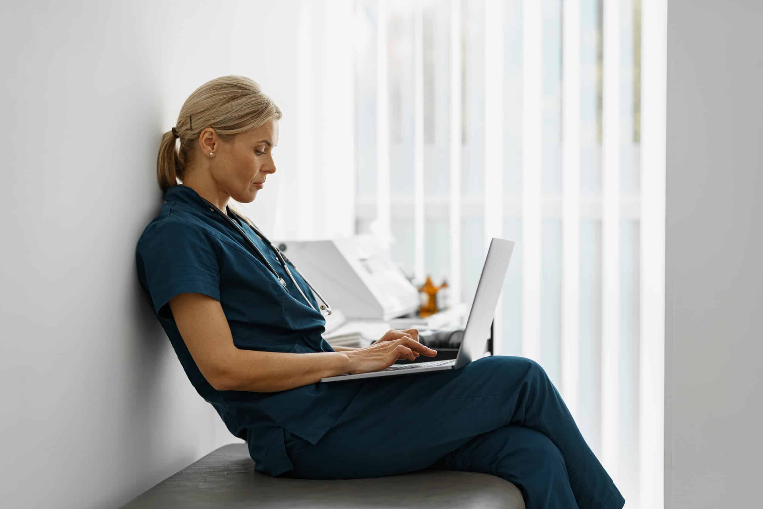 Female healthcare worker using laptop while working at doctor's office
