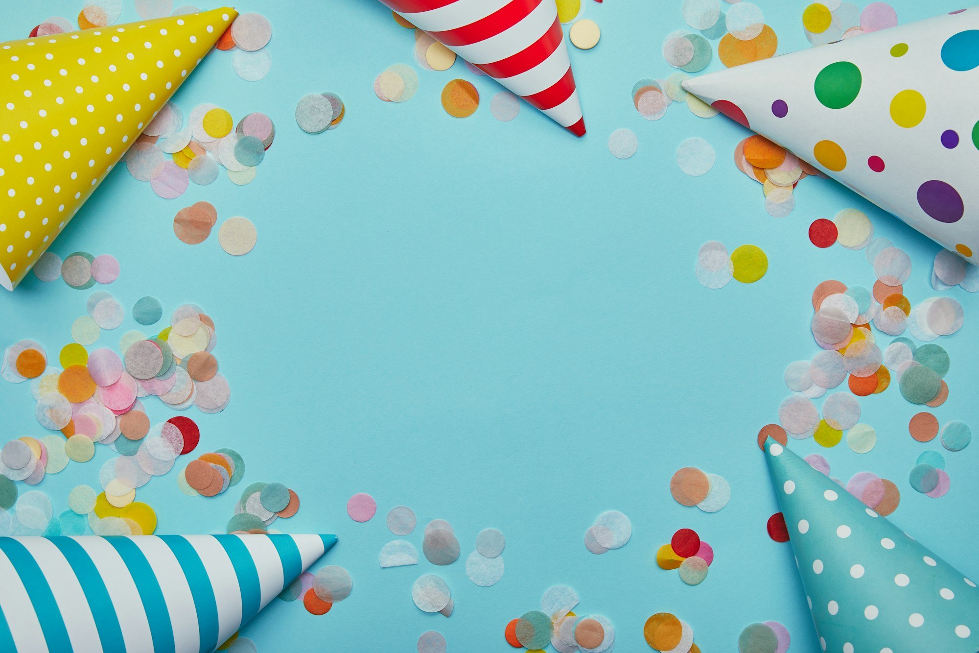 Top view of party hats and confetti on blue background