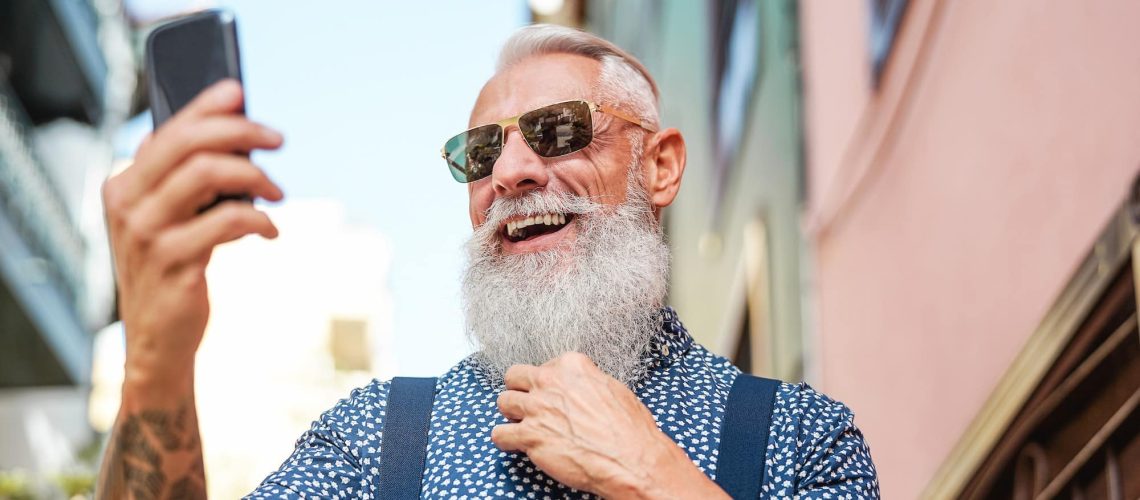 Bearded senior using mobile phone outdoor