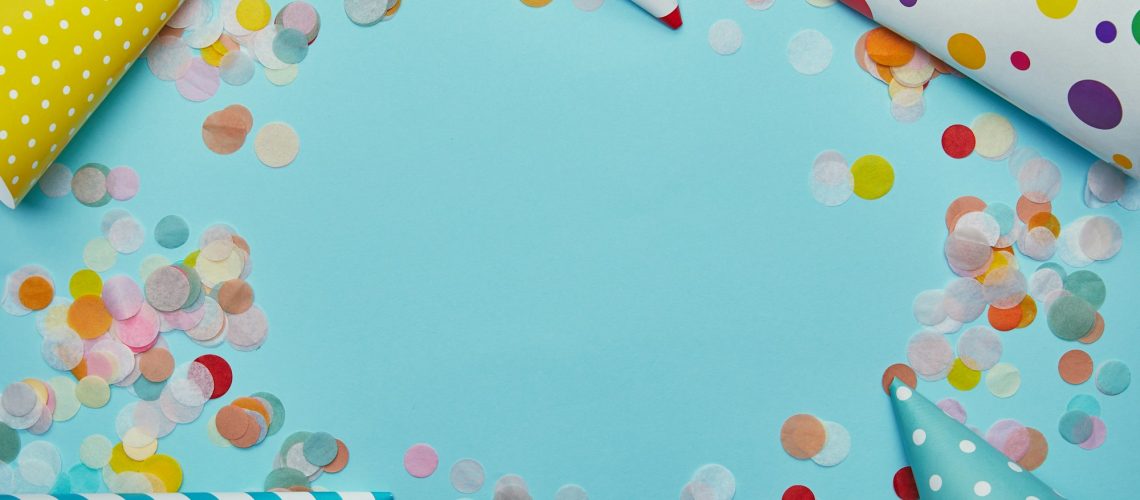 Top view of party hats and confetti on blue background